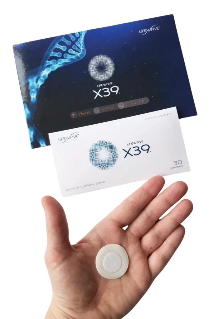 Hand holding a Lifewave X39 general wellness patch, with Lifewave X39 product packaging visible in the background.